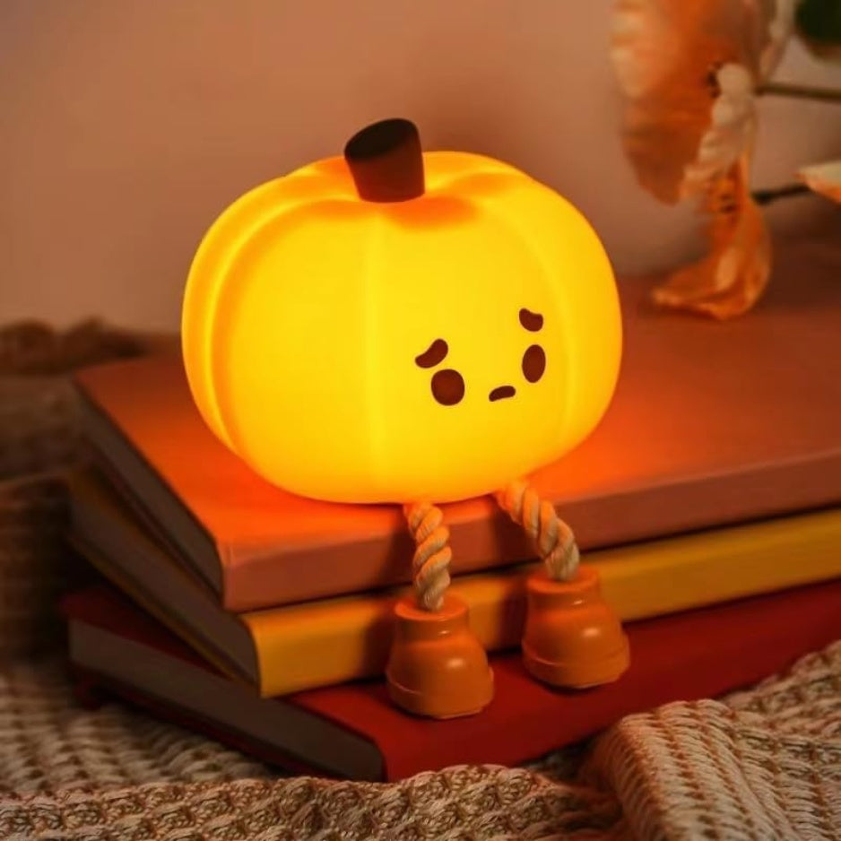 Silicone pumpkin night light glowing warm orange on a bedside table