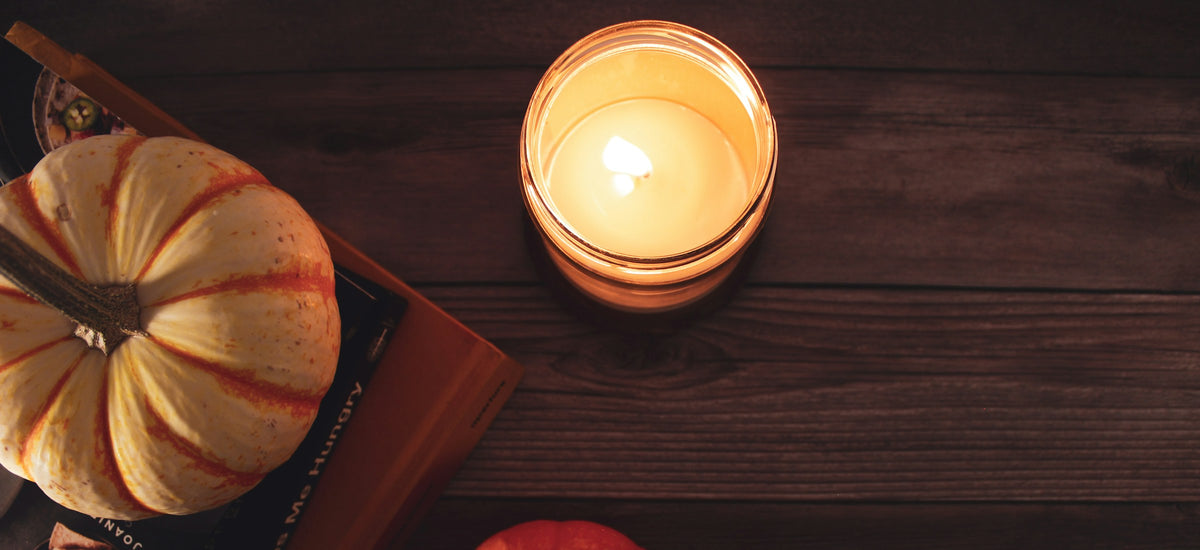 Lit candle beside a carved pumpkin in warm low light